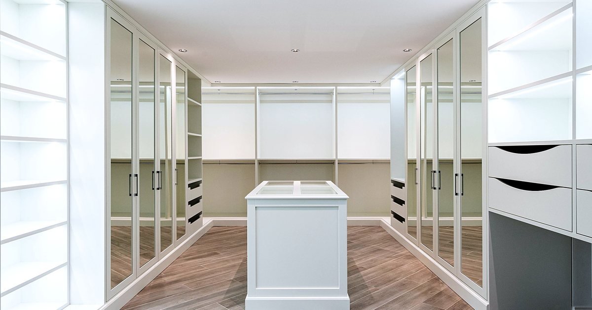 White dressing room with mirrored wardrobe doors, lit open shelves and a center island