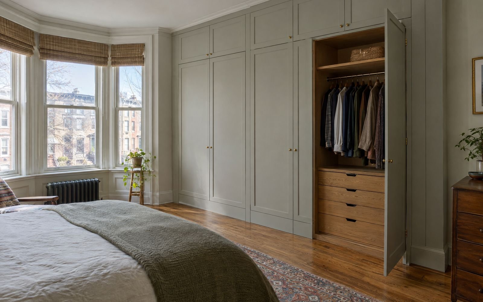 Painted wardrobe wall with an oak interior in a Bay Ridge limestone row house bedroom, design concept