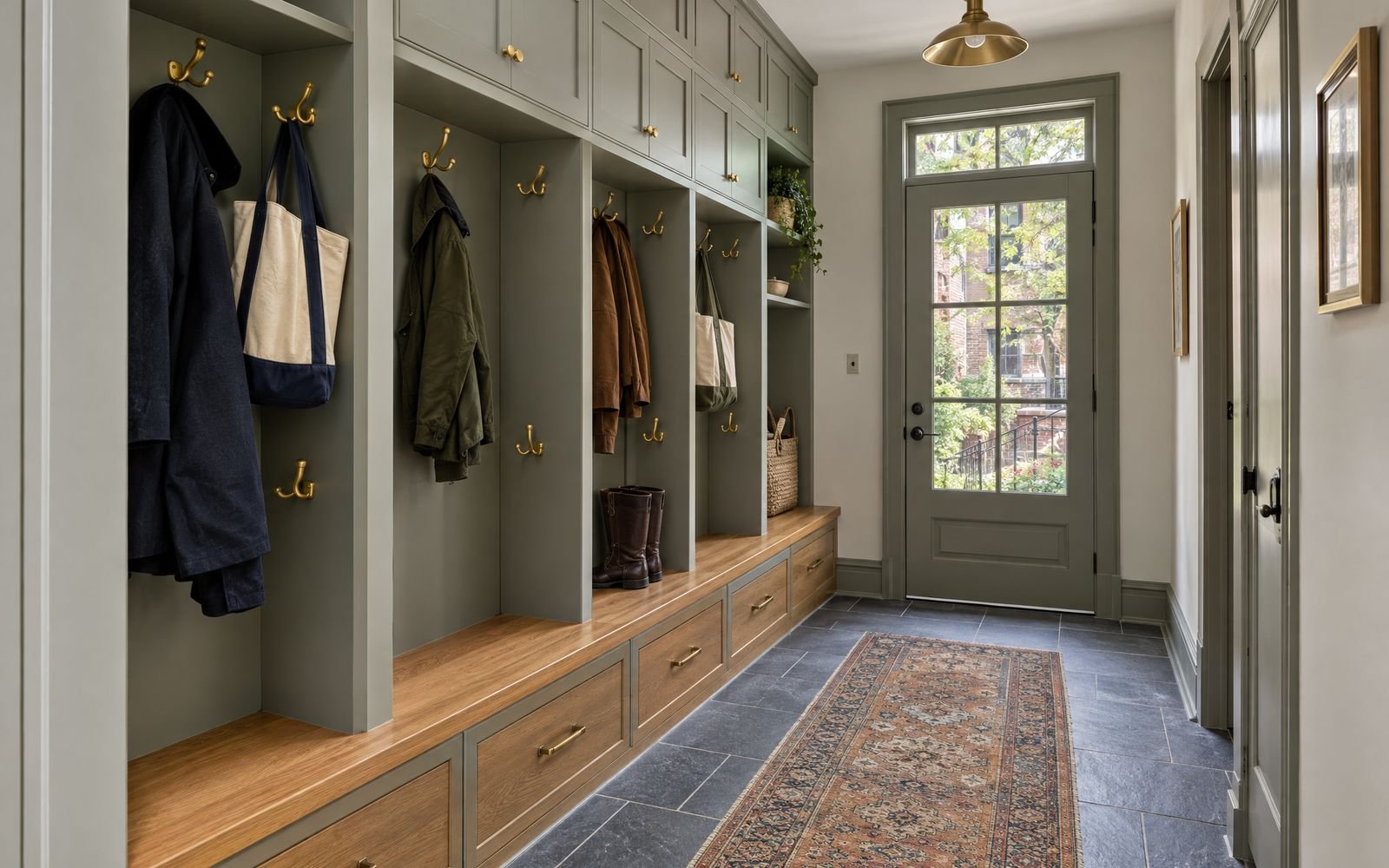 Mudroom with an oak bench, painted cubbies and brass coat hooks, design concept